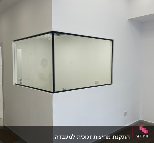 חלון זכוכית גדול עם מסגרת שחורה בקיר לבן